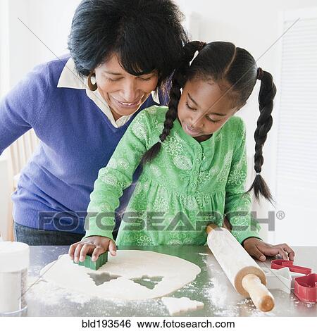 Stock Photograph - Black grandmother baking cookies with granddaughter. Fotosearch