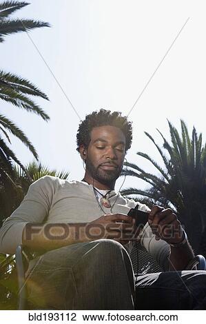 Black man listening to mp3 player outdoors View Large Photo Image Stock Image - Black man listening to mp3 player outdoors. Fotosearch