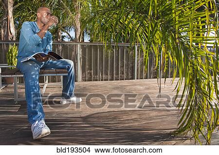 Black man reading book on patio View Large Photo Image Picture - Black man reading book on patio. Fotosearch