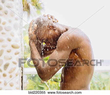 Stock Photography - Black man rinsing off in outdoor shower. Fotosearch