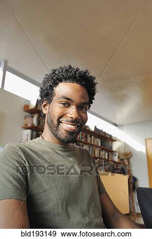 Black man smiling in living room View Large Photo Image Stock Photo - Black man smiling in living room. Fotosearch