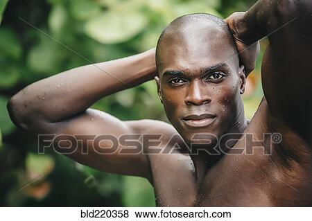 Stock Photo - Black man standing in lush garden. Fotosearch