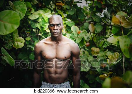 Stock Photograph - Black man standing in lush garden. Fotosearch