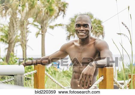 Stock Photo - Black man standing on beach walkway. Fotosearch