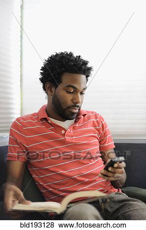 Stock Photo - Black man text messaging on cell phone. Fotosearch