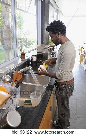 Stock Image - Black man washing dishes. Fotosearch