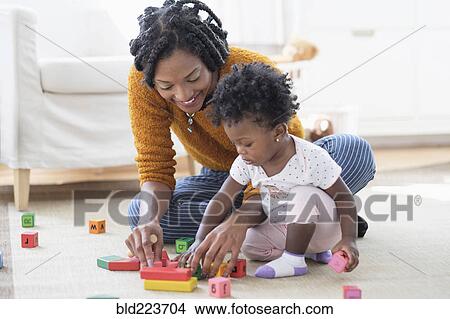 Black mother and baby daughter playing with blocks on carpet View Large Photo Image Picture - Black mother and baby daughter playing with blocks on carpet. Fotosearch