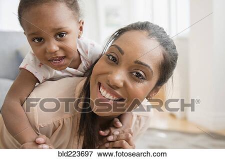 Black mother carrying baby daughter piggyback View Large Photo Image Stock Photo - Black mother carrying baby daughter piggyback. Fotosearch