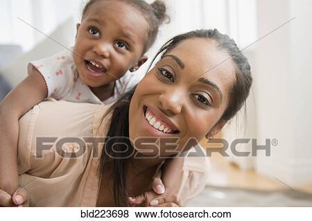 Black mother carrying baby daughter piggyback View Large Photo Image Stock Photo - Black mother carrying baby daughter piggyback. Fotosearch