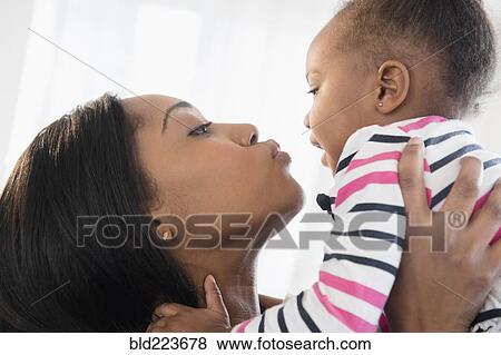 Black mother lifting baby daughter face to face View Large Photo Image Stock Photo - Black mother lifting baby daughter face to face. Fotosearch