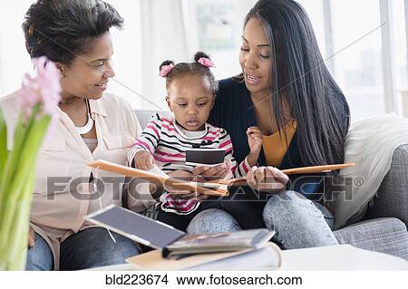 Black multi-generation family looking at photo album View Large Photo Image Picture - Black multi-generation family looking at photo album. Fotosearch