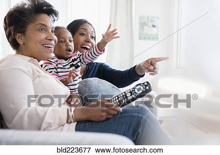 Stock Photo - Black multi-generation family watching exciting television. Fotosearch