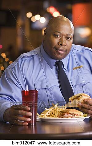 Black police officer eating unhealthy food View Large Photo Image Stock Photo - Black police officer eating unhealthy food. Fotosearch