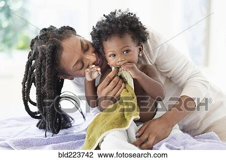 Stock Image - Black woman drying baby daughter with towels. Fotosearch