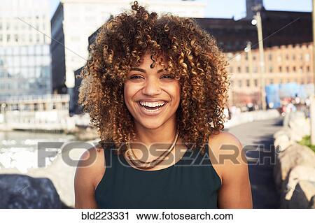 Stock Image - Black woman smiling at waterfront. Fotosearch