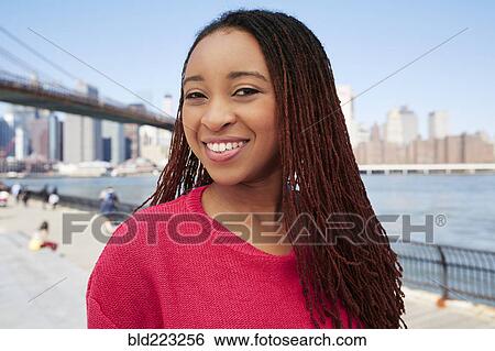 Stock Photograph - Black woman smiling at waterfront. Fotosearch