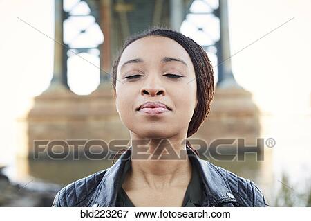 Stock Photo - Black woman thinking with eyes closed at bridge. Fotosearch