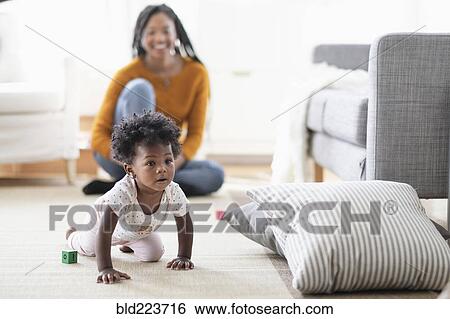 Black woman watching baby daughter crawl toward pillow View Large Photo Image Stock Photograph - Black woman watching baby daughter crawl toward pillow. Fotosearch