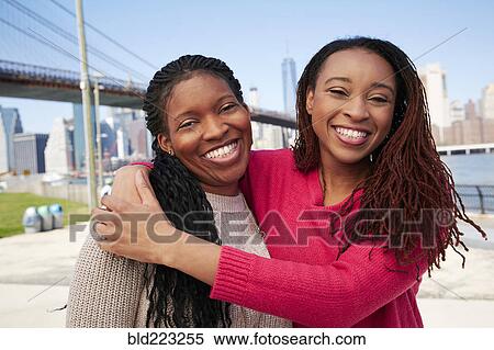 Stock Photography - Black women hugging at waterfront. Fotosearch