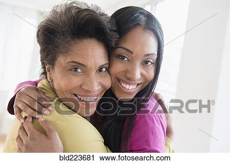 Stock Image - Black women hugging cheek to cheek. Fotosearch