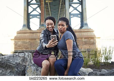 Stock Photography - Black women posing for selfie at bridge. Fotosearch