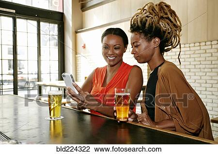 Black women using cell phone at bar View Large Photo Image Stock Image - Black women using cell phone at bar. Fotosearch