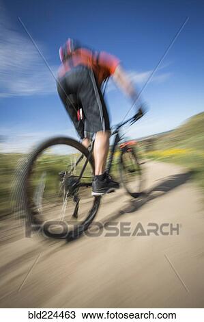 Stock Image - Blurred view of man riding mountain bike. Fotosearch