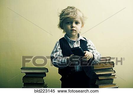 Boy holding cell phone near stacks of books View Large Photo Image Stock Photography - Boy holding cell phone near stacks of books. Fotosearch