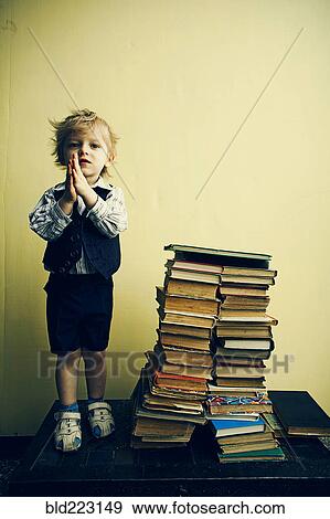 Boy standing near stacks of books View Large Photo Image Stock Photo - Boy standing near stacks of books. Fotosearch