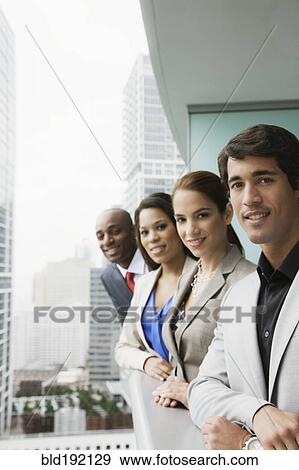 Stock Photo - Business people leaning on railing of urban balcony. Fotosearch