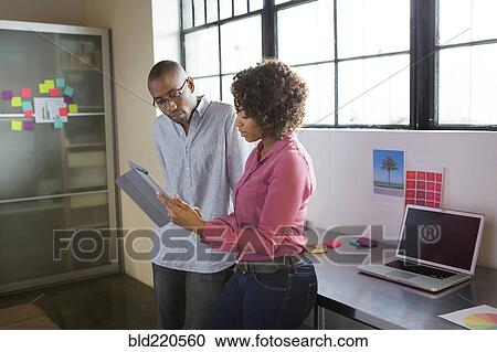 Stock Image - Business people reading digital tablet in office. Fotosearch
