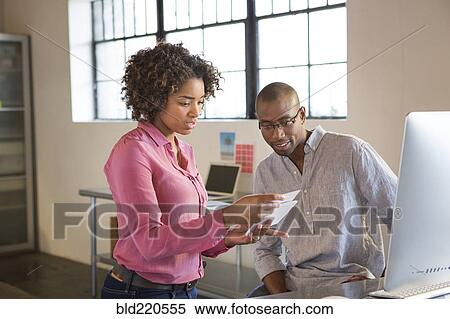 Stock Photography - Business people reading papers in office. Fotosearch