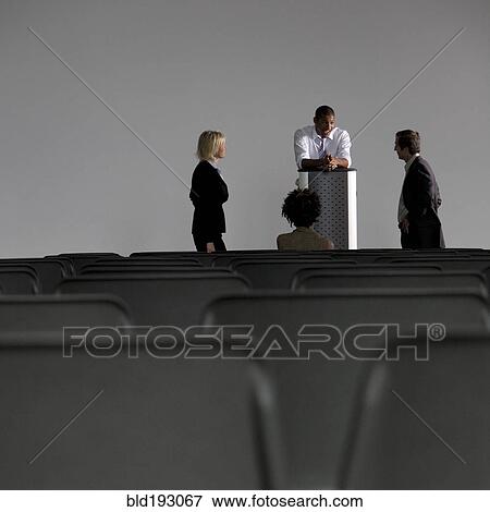 Stock Photo - Business people talking in empty auditorium. Fotosearch