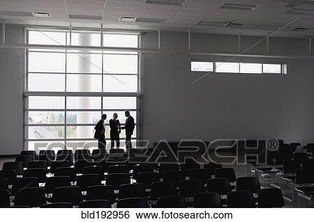 Stock Photograph - Business people talking in empty auditorium. Fotosearch