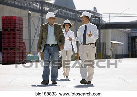 Stock Image - Business people walking outside factory. Fotosearch