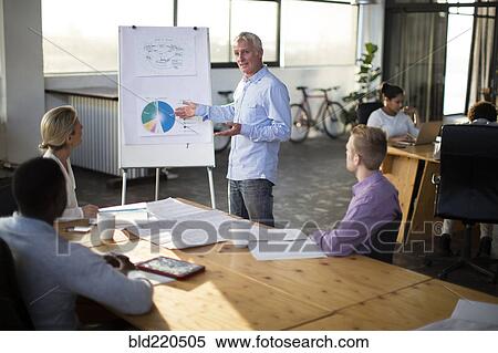 Stock Photography - Businessman giving presentation in office meeting. Fotosearch