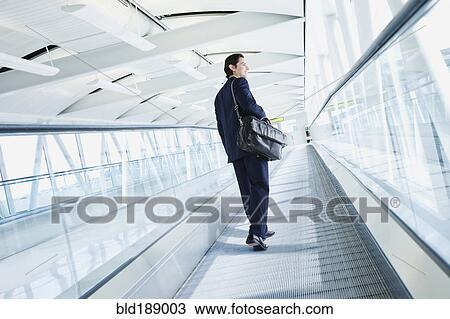 Businessman on moving walkway in airport View Large Photo Image Stock Image - Businessman on moving walkway in airport. Fotosearch