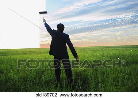 Stock Image - Businessman painting sky in field. Fotosearch