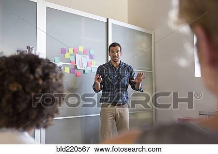 Businessman talking to colleagues in office meeting View Large Photo Image Stock Photo - Businessman talking to colleagues in office meeting. Fotosearch