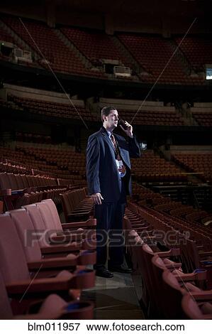 Stock Photo - Businessman using walkie-talkie in empty auditorium. Fotosearch