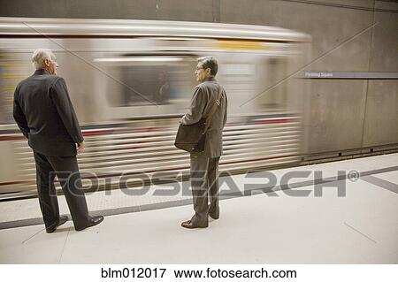 Stock Photo - Businessmen waiting on subway platform. Fotosearch