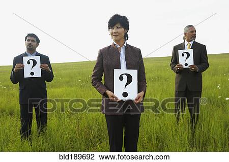 Stock Image - Businesspeople holding question marks in field. Fotosearch