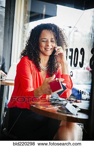 Stock Photo - Businesswoman examining fabric swatches in cafe. Fotosearch