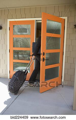 Businesswoman pulling rolling suitcase through doorway View Large Photo Image Stock Photo - Businesswoman pulling rolling suitcase through doorway. Fotosearch