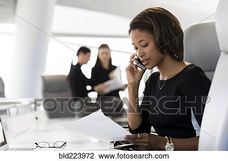 Businesswoman reading paperwork talking on cell phone View Large Photo Image Stock Image - Businesswoman reading paperwork talking on cell phone. Fotosearch