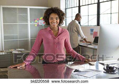 Stock Photo - Businesswoman smiling at desk in office. Fotosearch