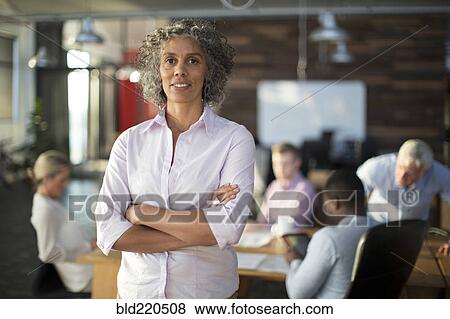 Businesswoman standing in office View Large Photo Image Stock Photo - Businesswoman standing in office. Fotosearch