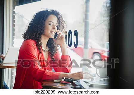 Stock Photo - Businesswoman talking on cell phone in cafe. Fotosearch