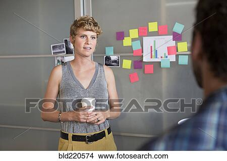 Picture - Businesswoman talking to colleague in office. Fotosearch
