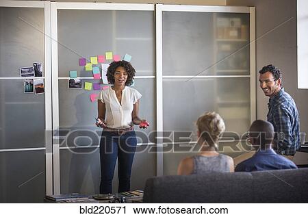 Stock Image - Businesswoman talking to colleagues in office meeting. Fotosearch